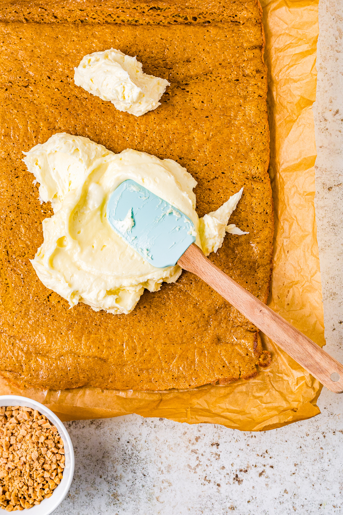 Cream cheese frosting being spread onto a pumpkin cake roll.