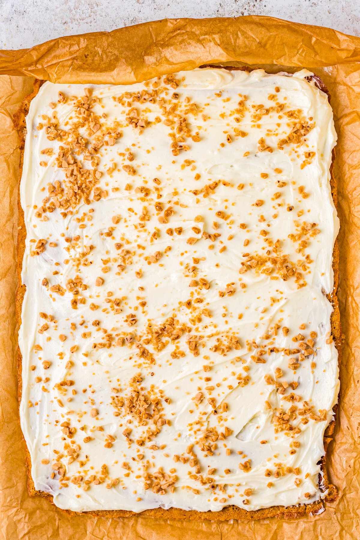 A thin pumpkin jelly roll cake spread with creamy filling and sprinkled with toffee bits.