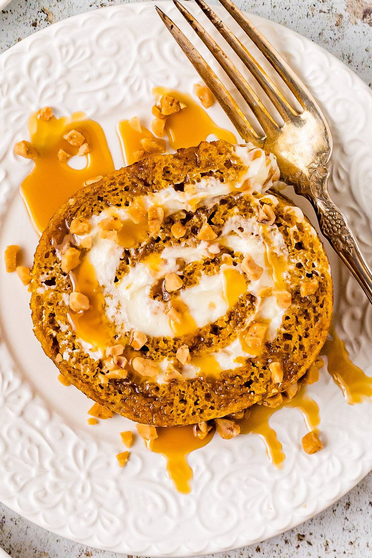 A slice of pumpkin jelly roll cake with creamy filling, on a dessert plate.