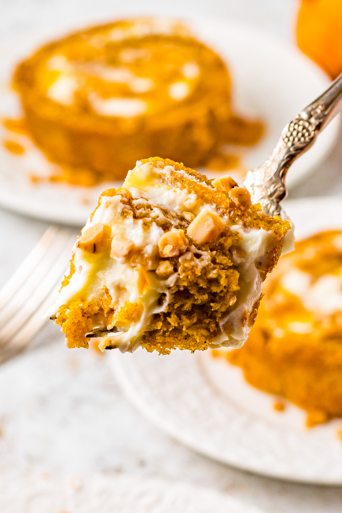 A bite of pumpkin roll cake being lifted toward the camera on a fork.