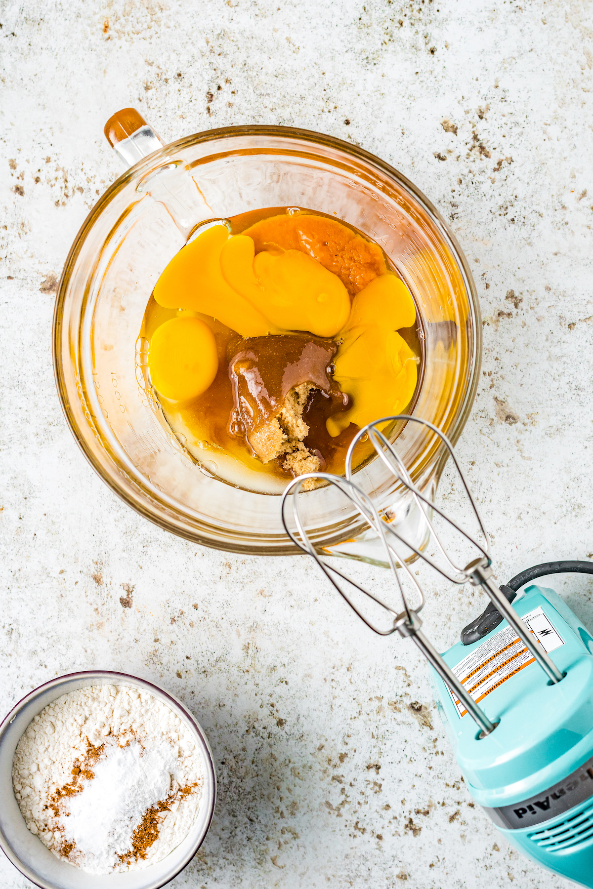 eggs, pumpkin, and other wet batter ingredients being beaten in a mixing bowl.