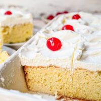 A side view of Tres Leches Cake still in the pan with a few slices missing.