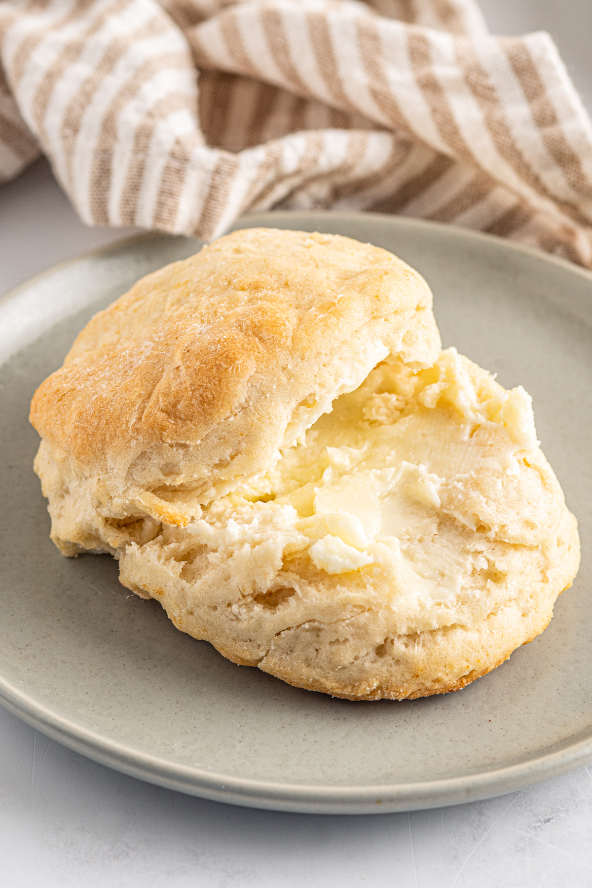 A split, buttered biscuit on a small plate.