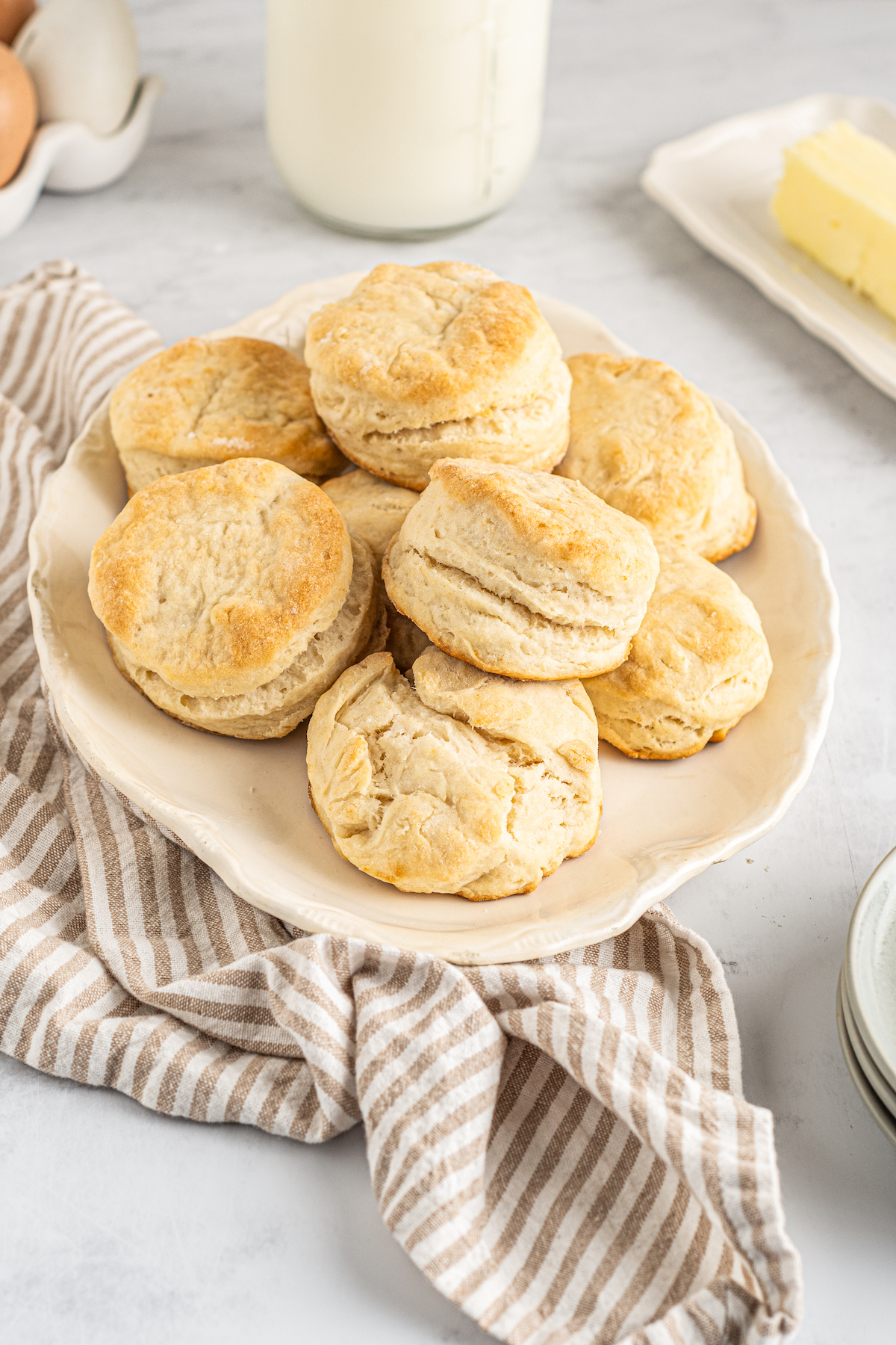 7-Up biscuits piled on a plate. A cloth napkin, a butter dish, and other items are arranged artistically around the table.