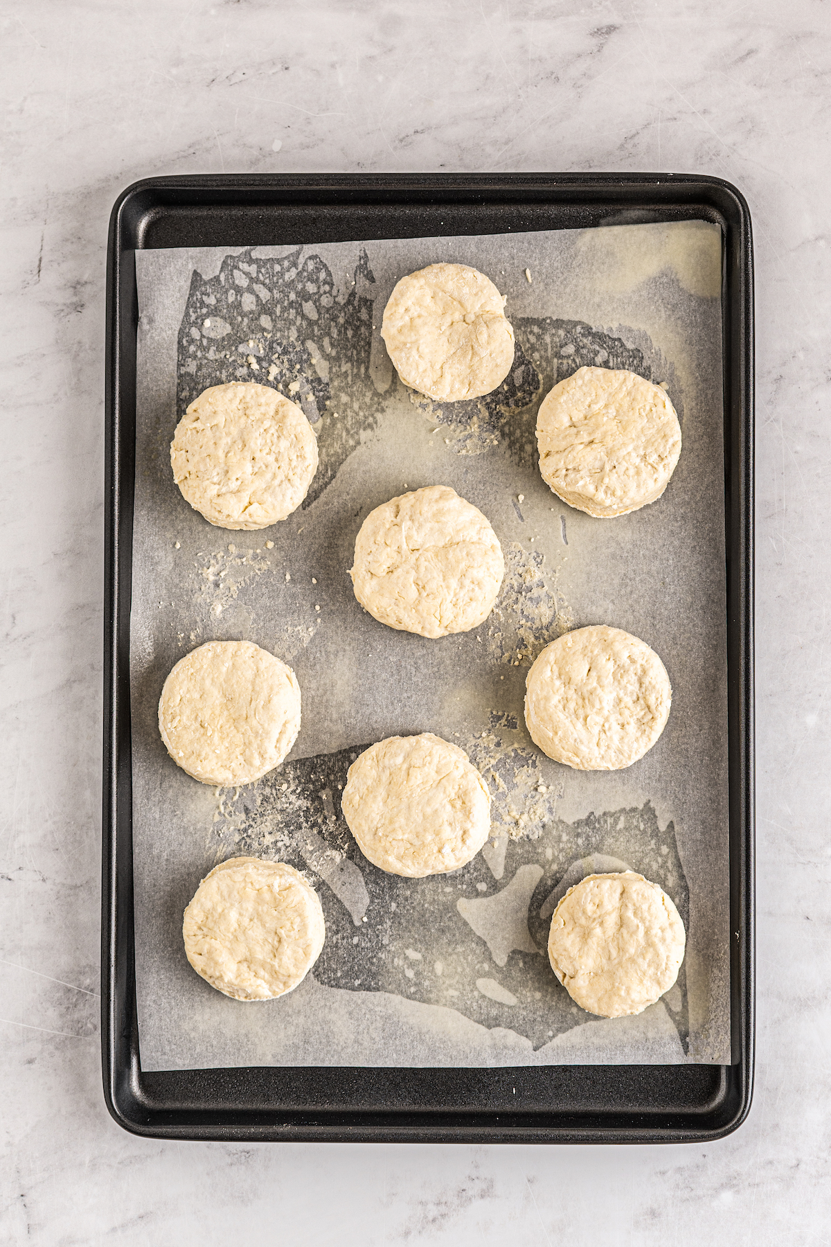 Biscuits arranged on a parchment-lined baking sheet.