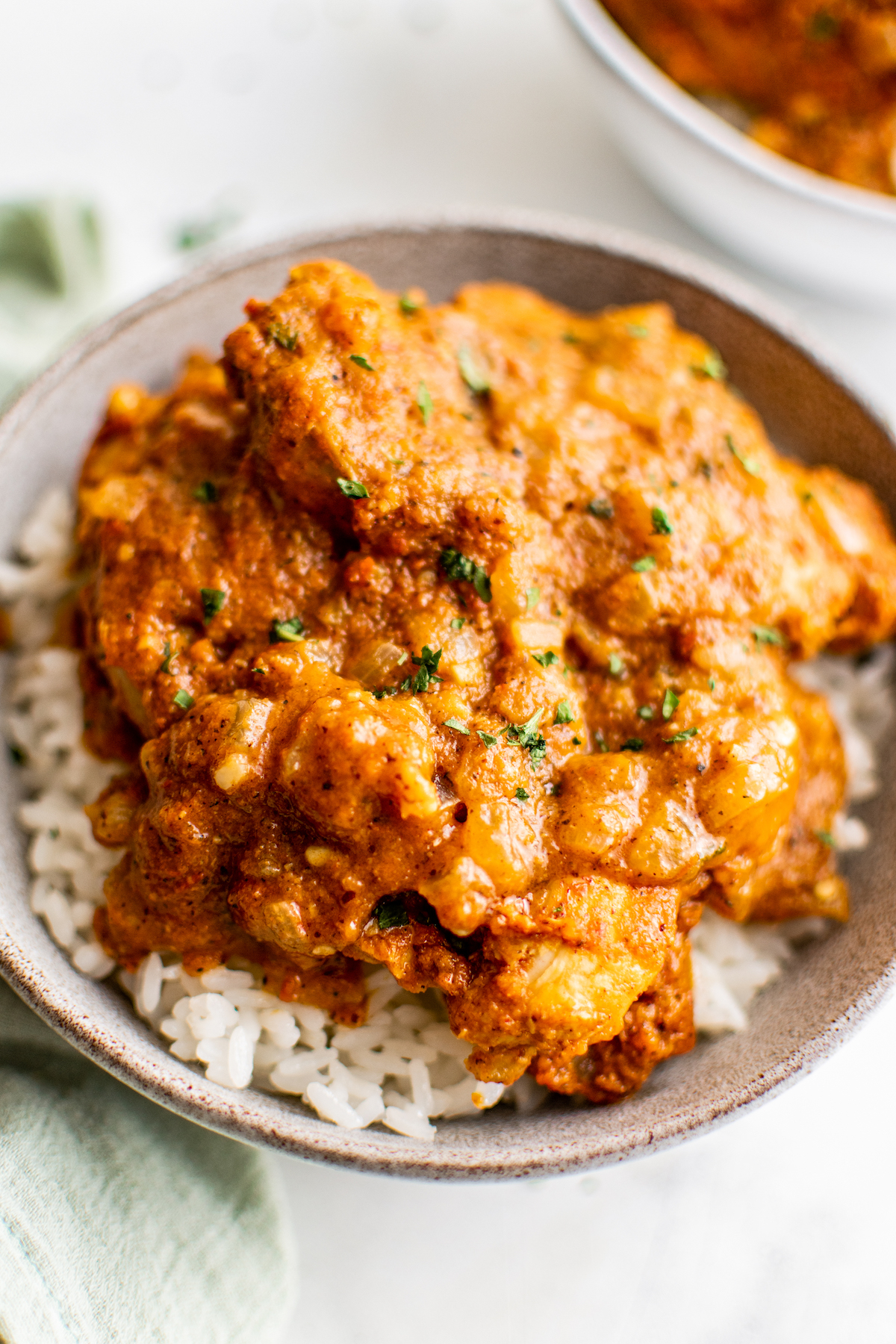 A bowl of achiote chicken on top of white rice, garnished with cilantro