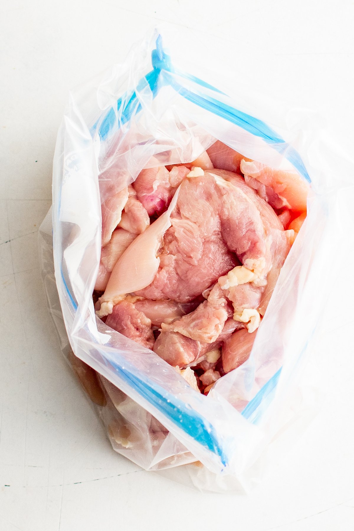 An open ziplock back with raw chicken thighs in it