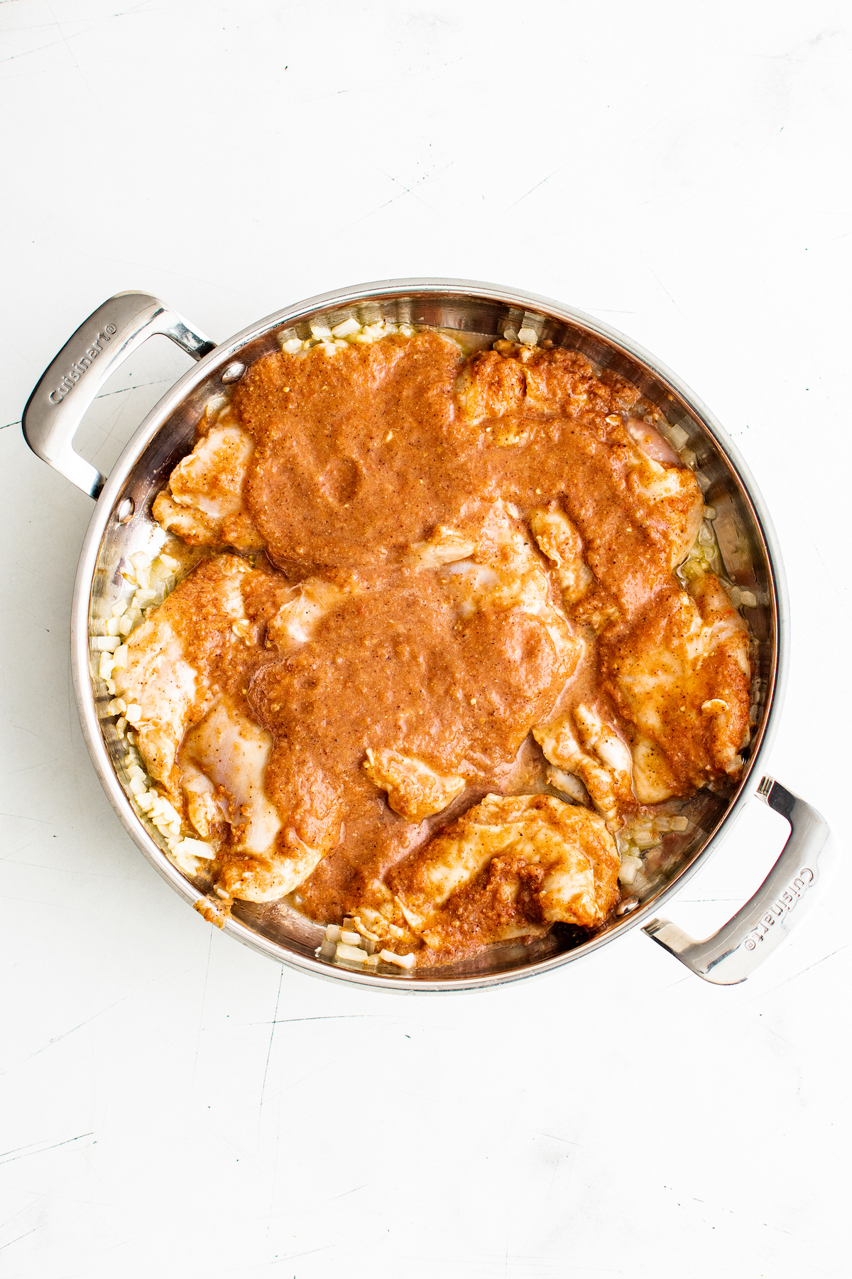 Aerial view of achiote chicken cooking in a pan, with the top still raw