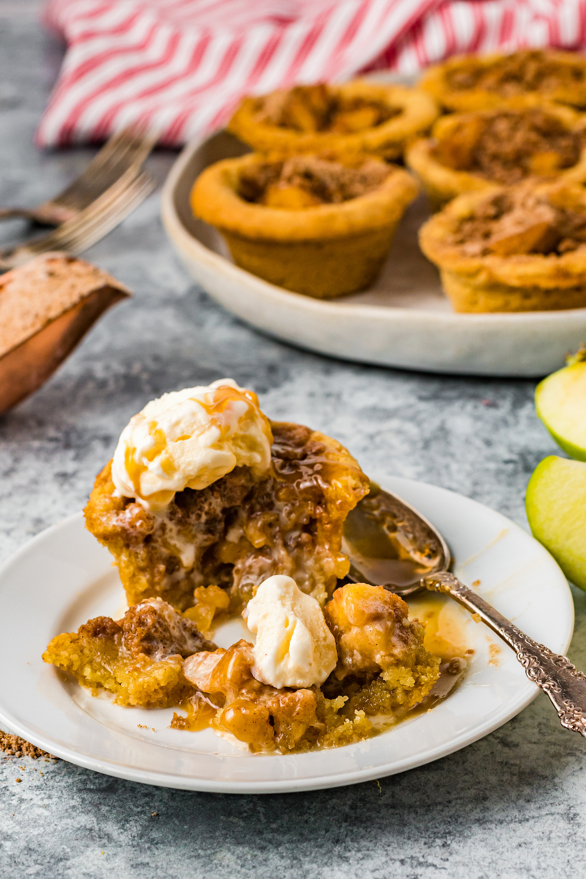 An mini apple pie on a dessert plate. It has been cut into to show the texture of the filling.