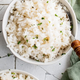 Puerto Rican white rice in a white bowl with a spoon.