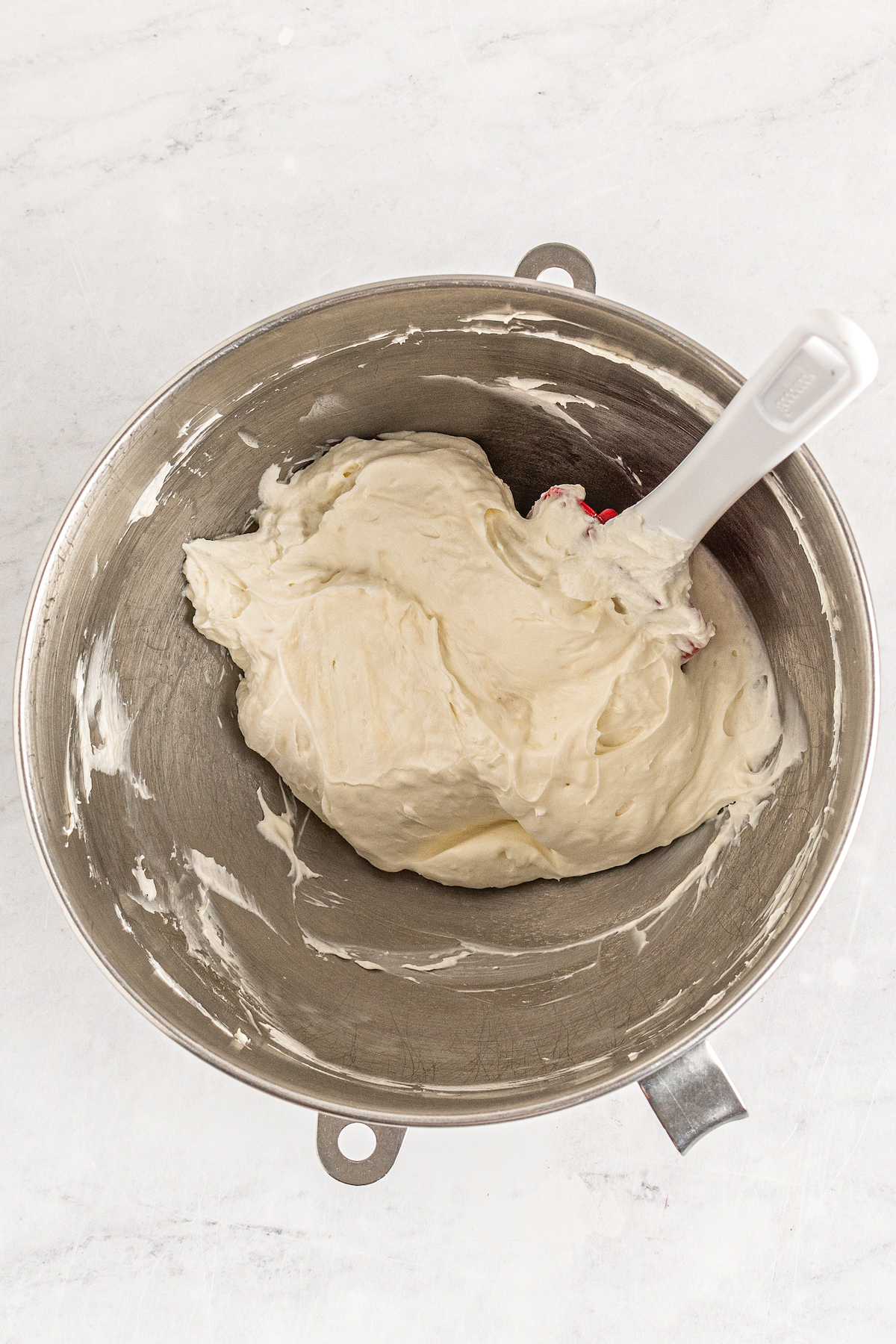 Frosting in a mixing bowl, with a spatula