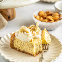 A slice of banana pudding cheesecake with a bite taken out on a fork on the plate