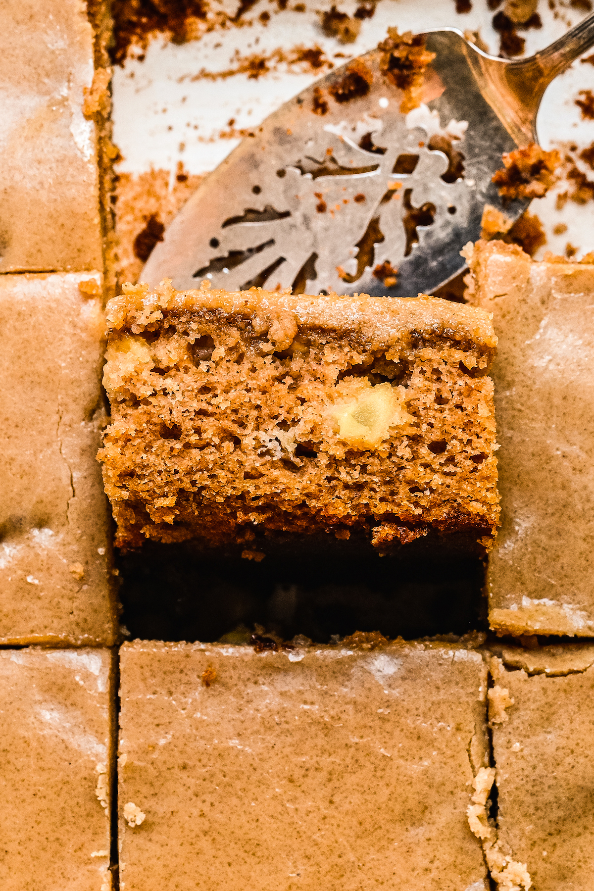 A slice of brown sugar apple cake being taken out of the pan