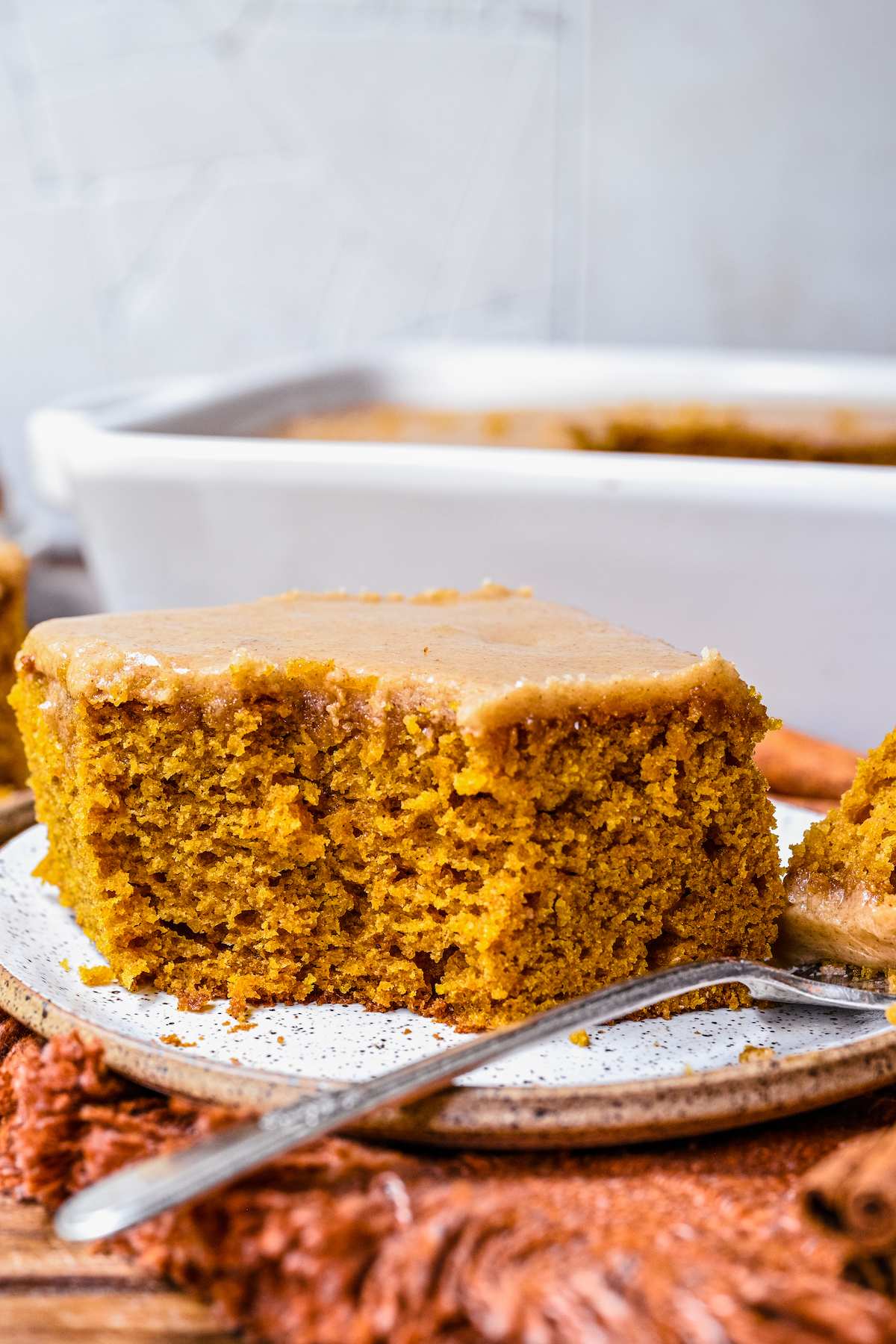 A square of pumpkin cake with a bite-sized piece resting on a fork.