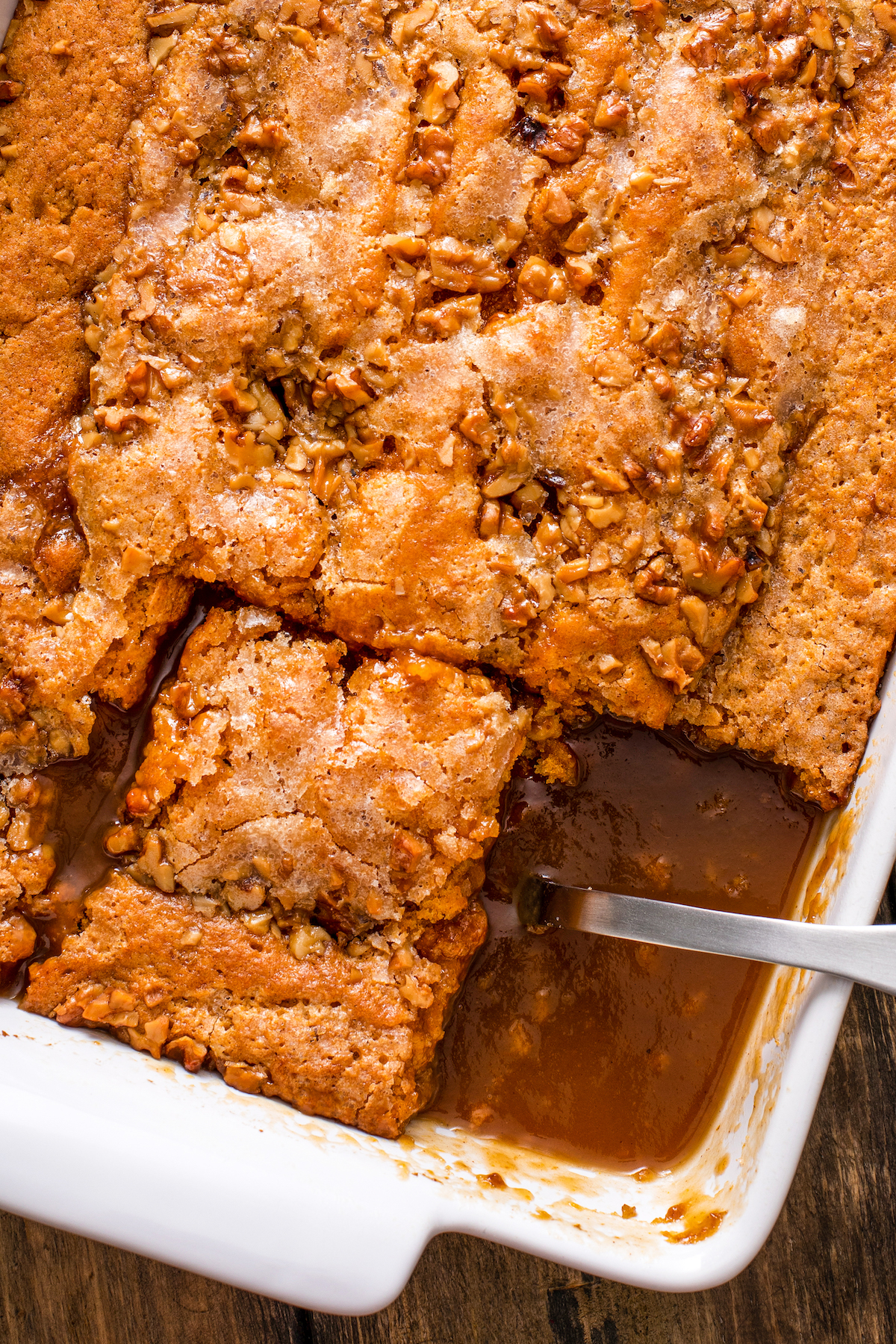 Close-up shot of caramel pumpkin cobbler, with one square removed to show the caramel sauce at the bottom of the pan.