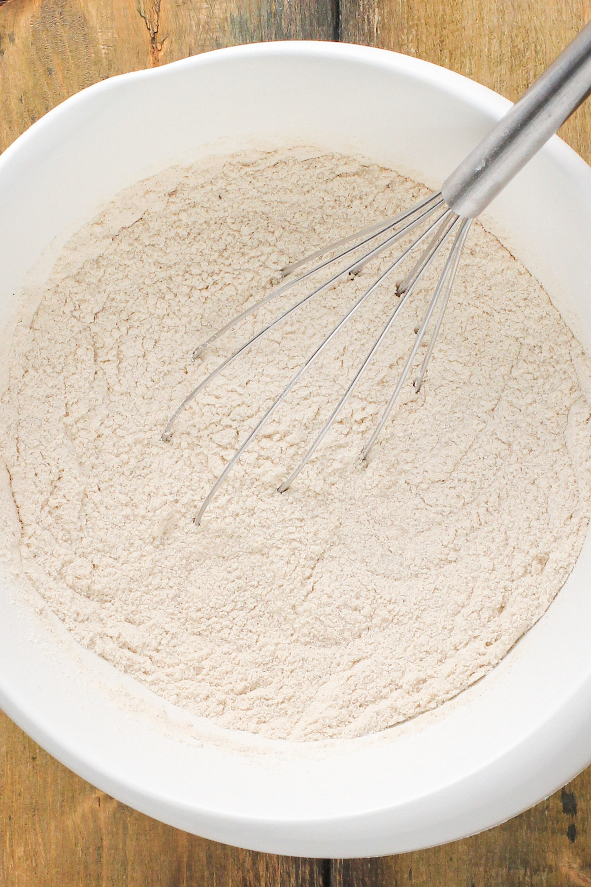 Dry ingredients in a mixing bowl with a whisk.