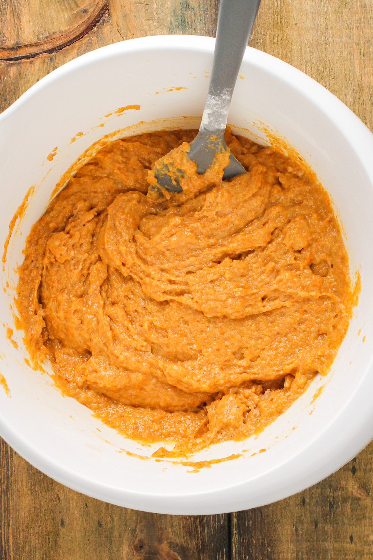 A thick pumpkin batter in a mixing bowl with a metal spoon.