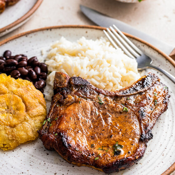 A plate with chuleta frita, rice, and beans