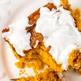 Pumpkin cinnamon cake on a white plate with a fork cutting a bite.