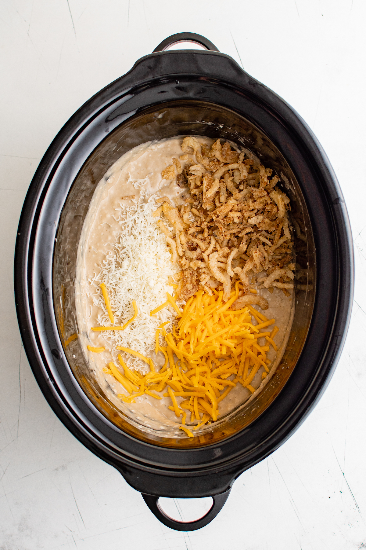 Creamy mushroom sauce in a slow cooker, with cheese and french fried onions on top.