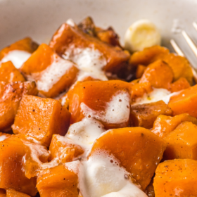 Sweet potatoes in a bowl with marshmallows melted on top.