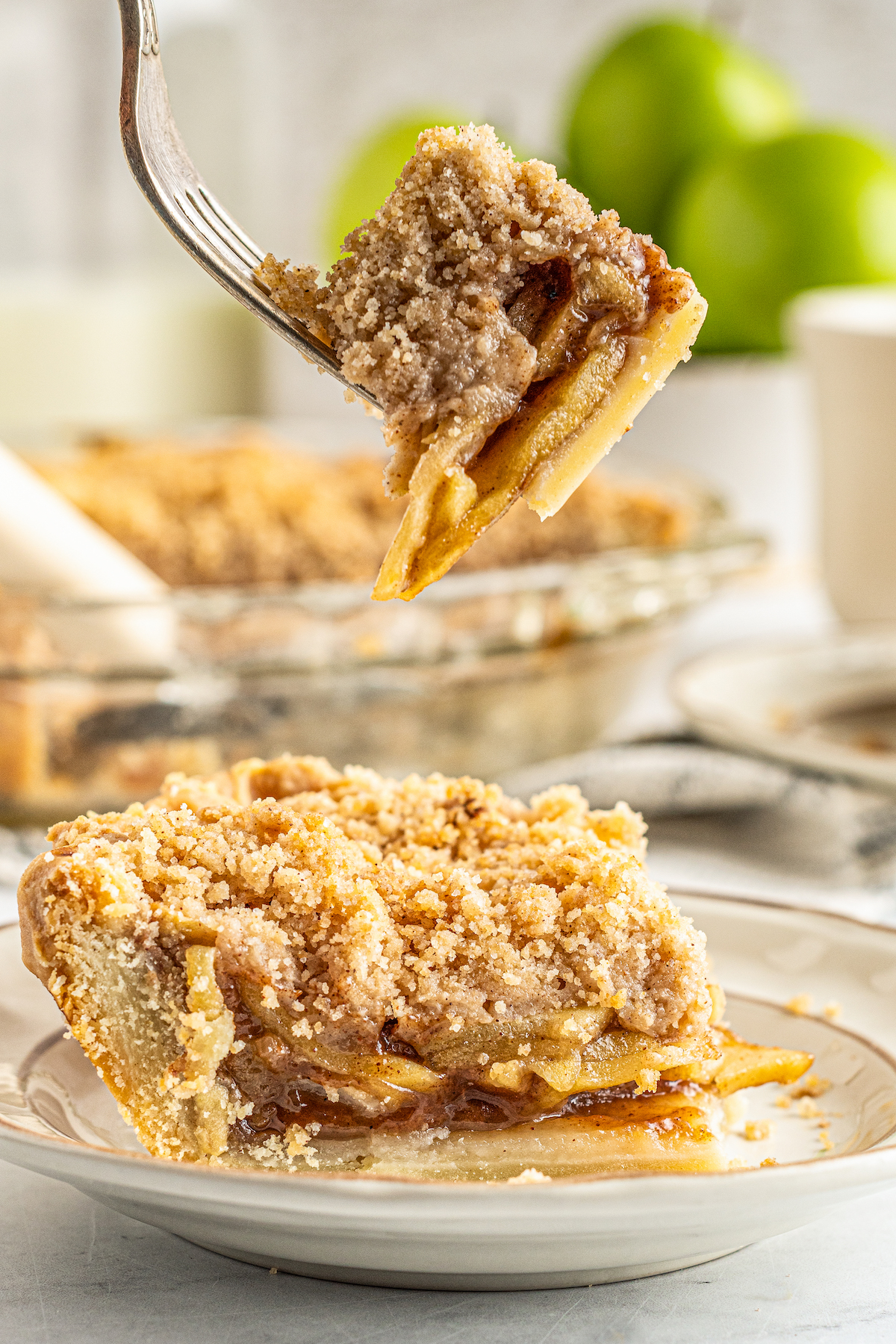 A slice of Dutch apple pie on a plate, with a fork holding a bite over the pie
