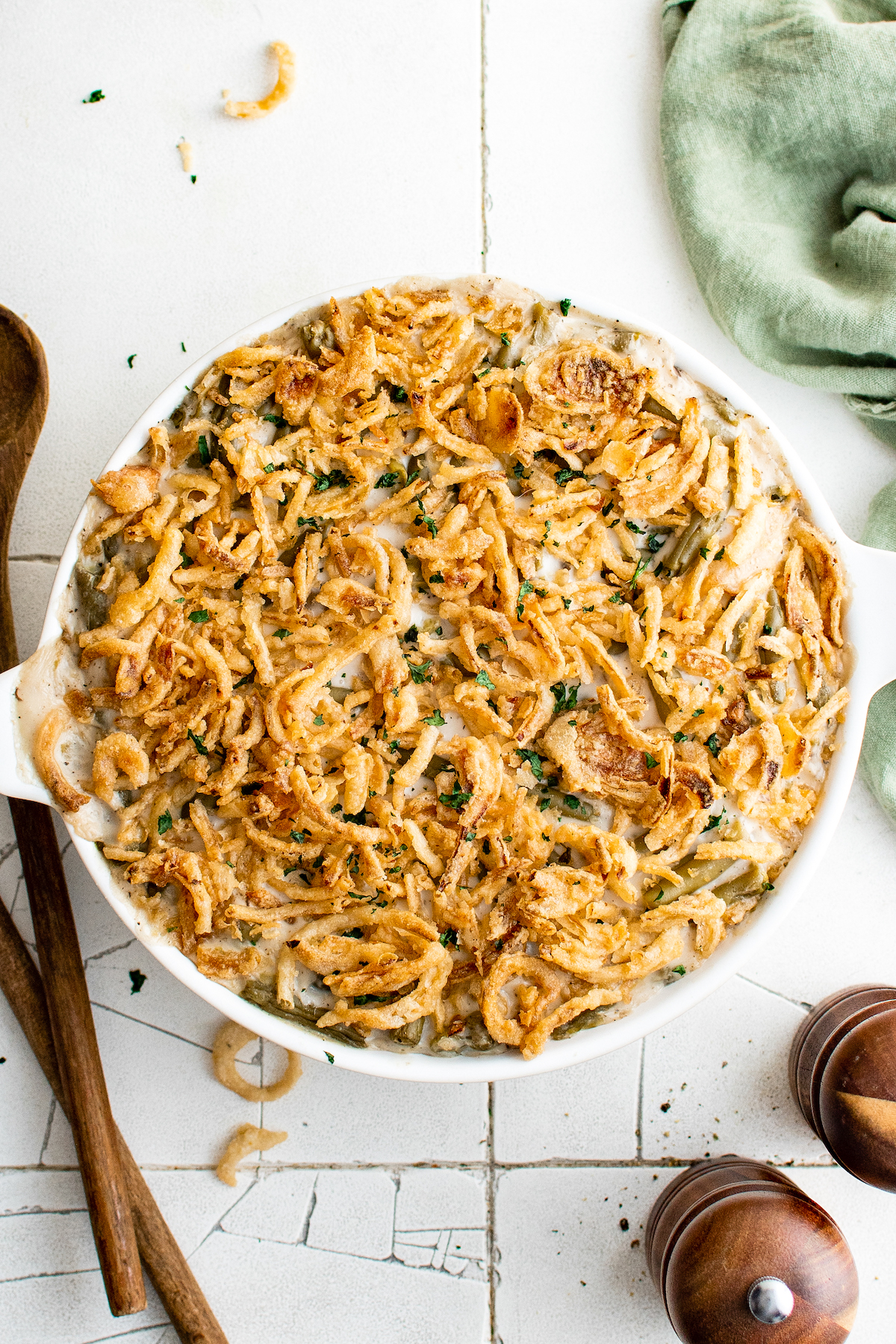 Classic green bean casserole with canned green beans in a round casserole dish topped with french fried onions on top.