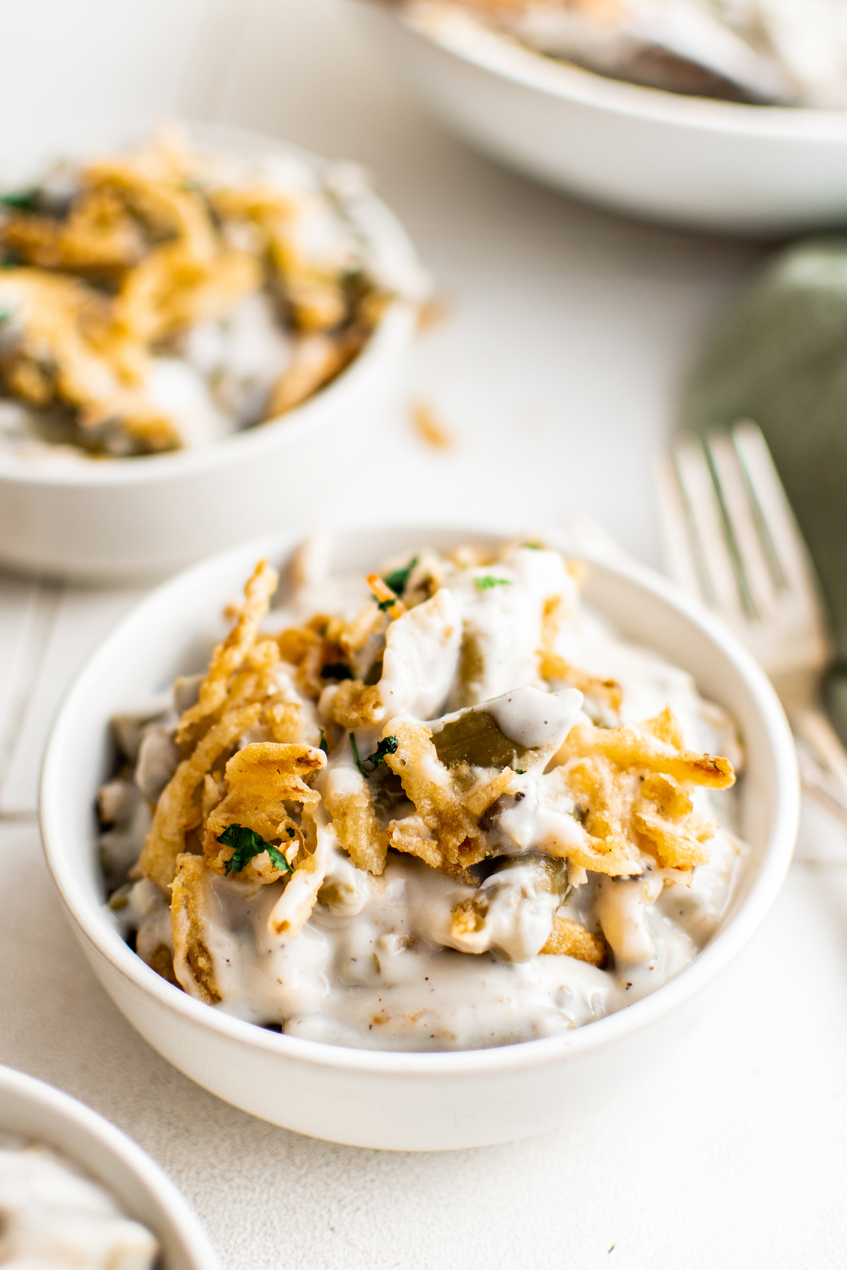 Easy green bean casserole in a small white bowl with a fork.