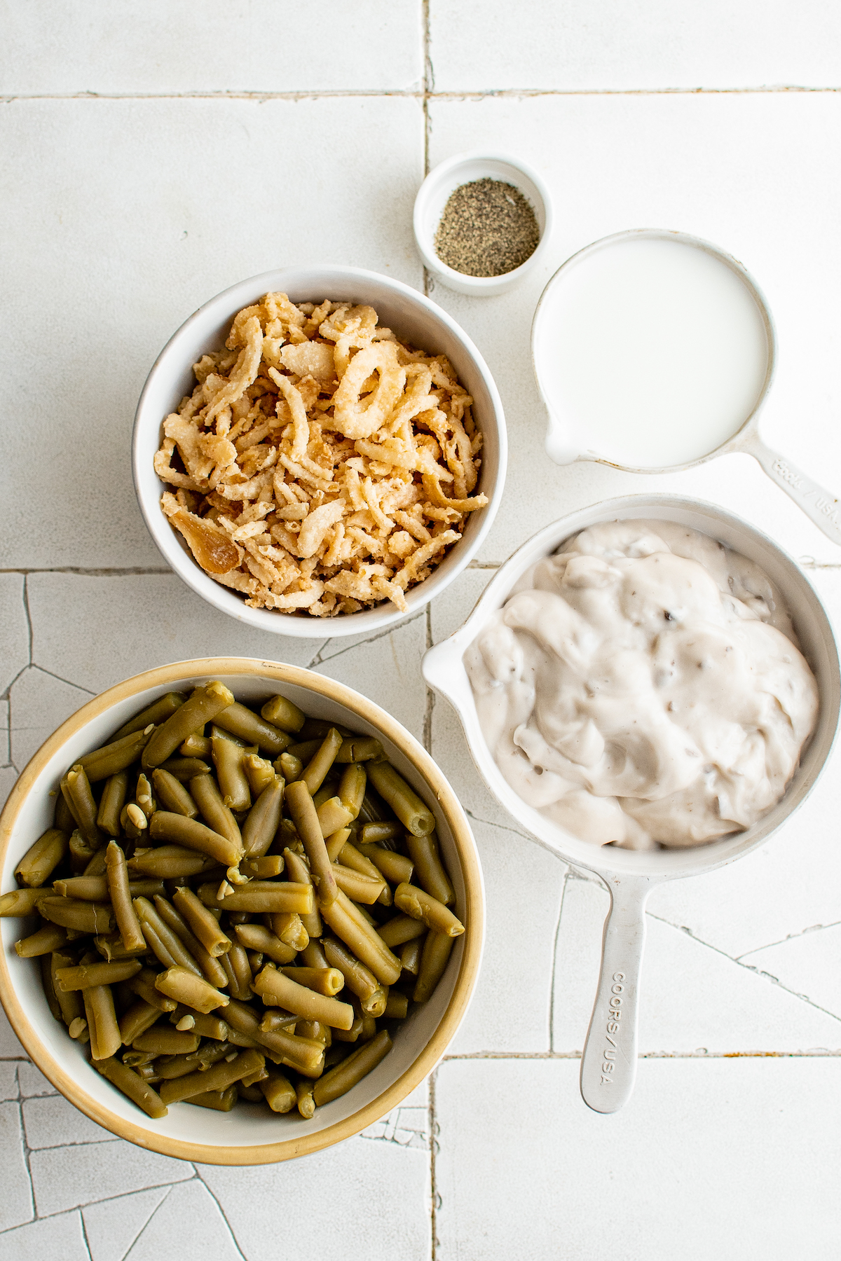 Ingredients for this easy green bean casserole recipe from the top: Black pepper, milk, mushroom soup, green beans, and french fried onions.
