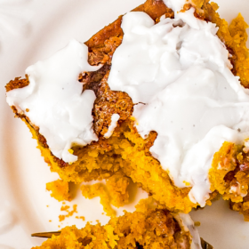 Pumpkin cinnamon cake on a white plate with a fork cutting a bite.