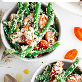 Two bowls of green bean salad with a spoon with dressing.