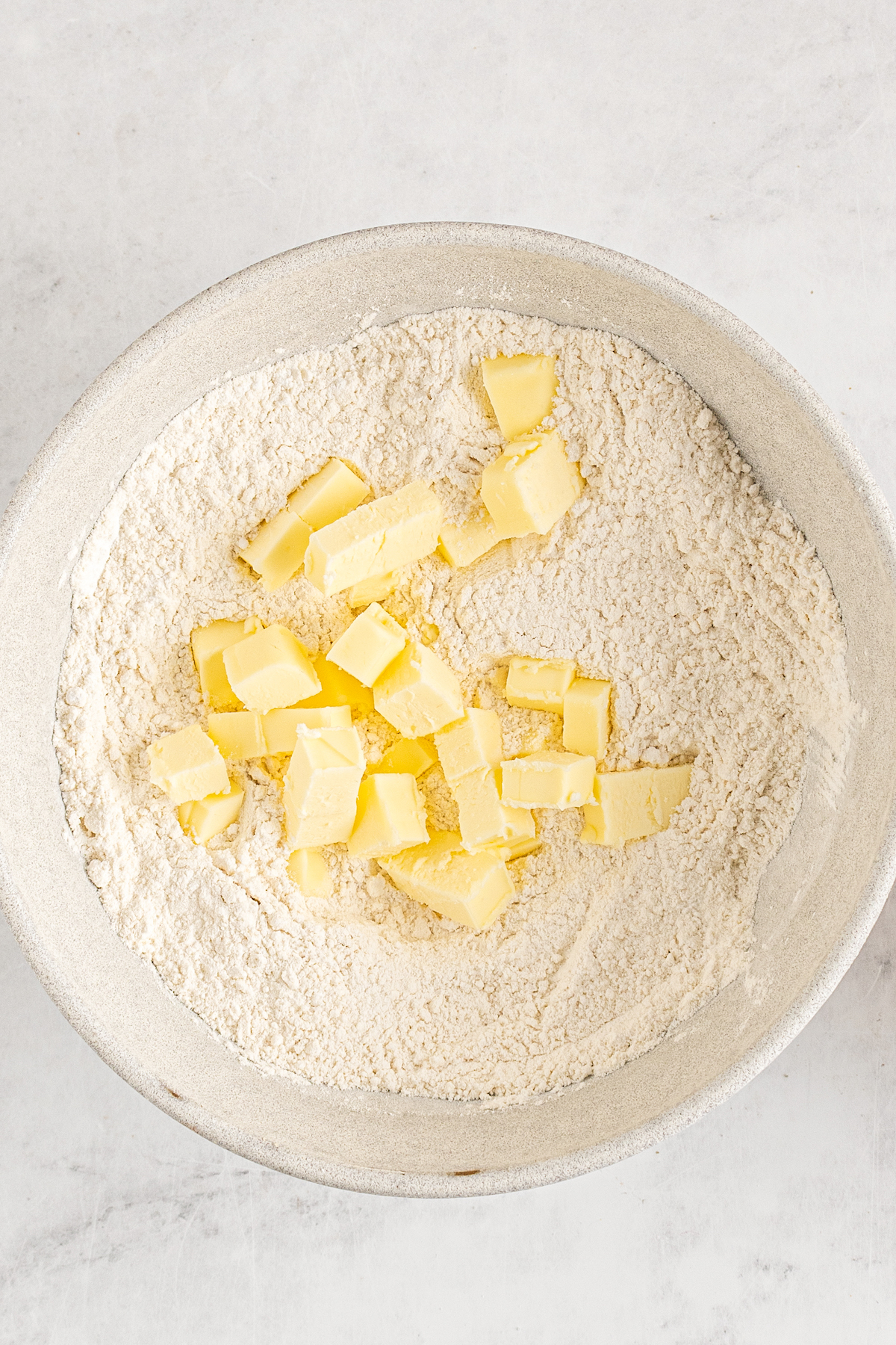 Chopped butter in a bowl of dry ingredients.