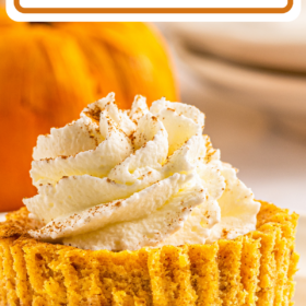A mini pumpkin cheesecake with a graham cracker crust with whip cream on top.