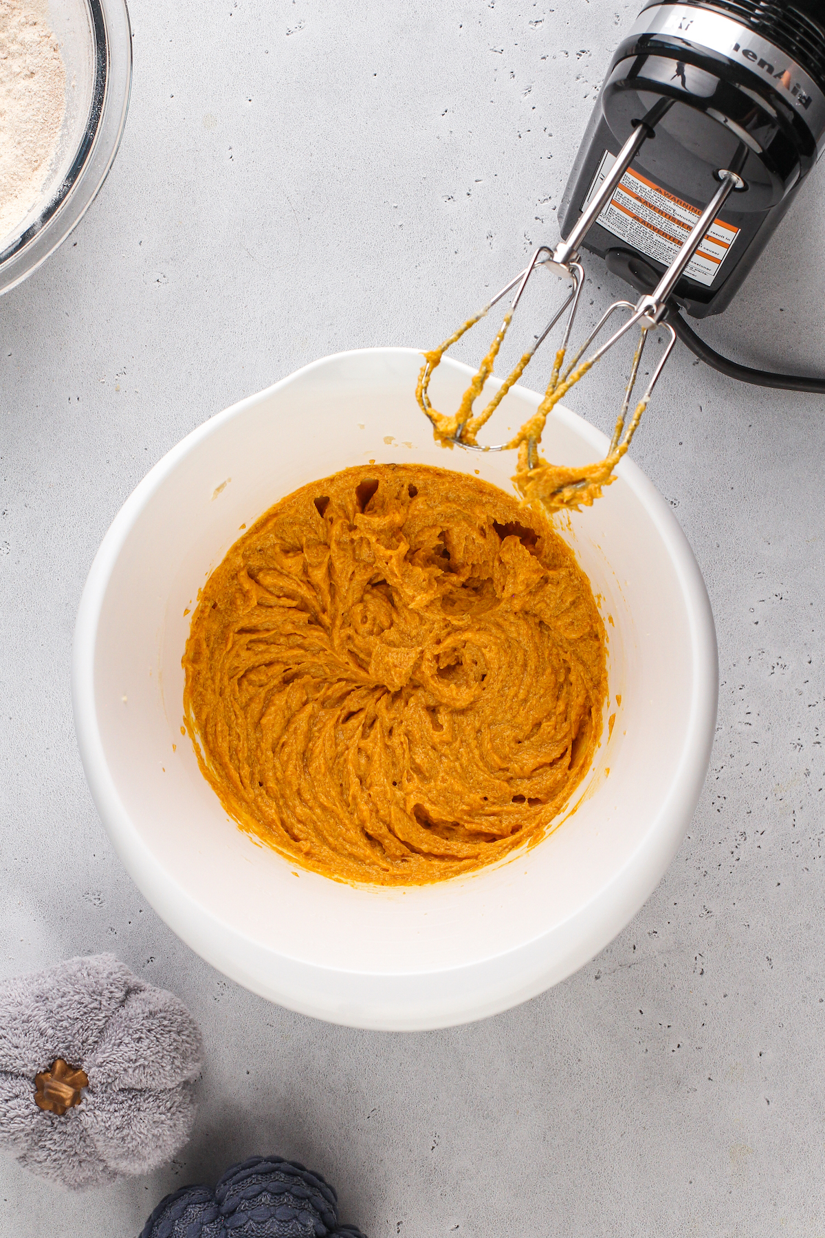 Pumpkin blondie batter in a mixing bowl with a hand mixer.