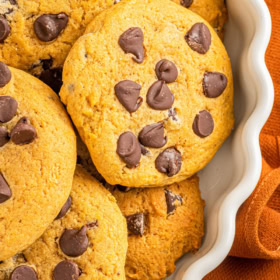 Pumpkin cookies stacked on a serving plate.