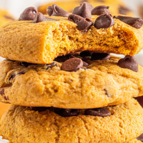 A stack of pumpkin cookies with chocolate chips on a white plate.