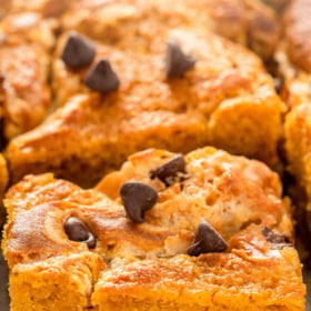 A slice of pumpkin cake with cream cheese, chocolate chips and coconut inside.