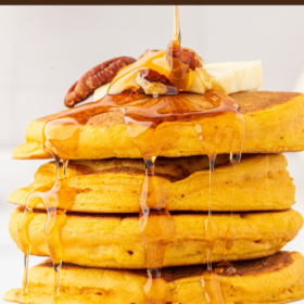 A large stack of pumpkin pancakes with maple syrup being drizzled on top.