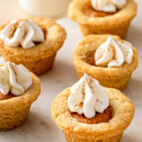 Mini pumpkin cookie cups garnished with whipped cream and pumpkin pie spice.