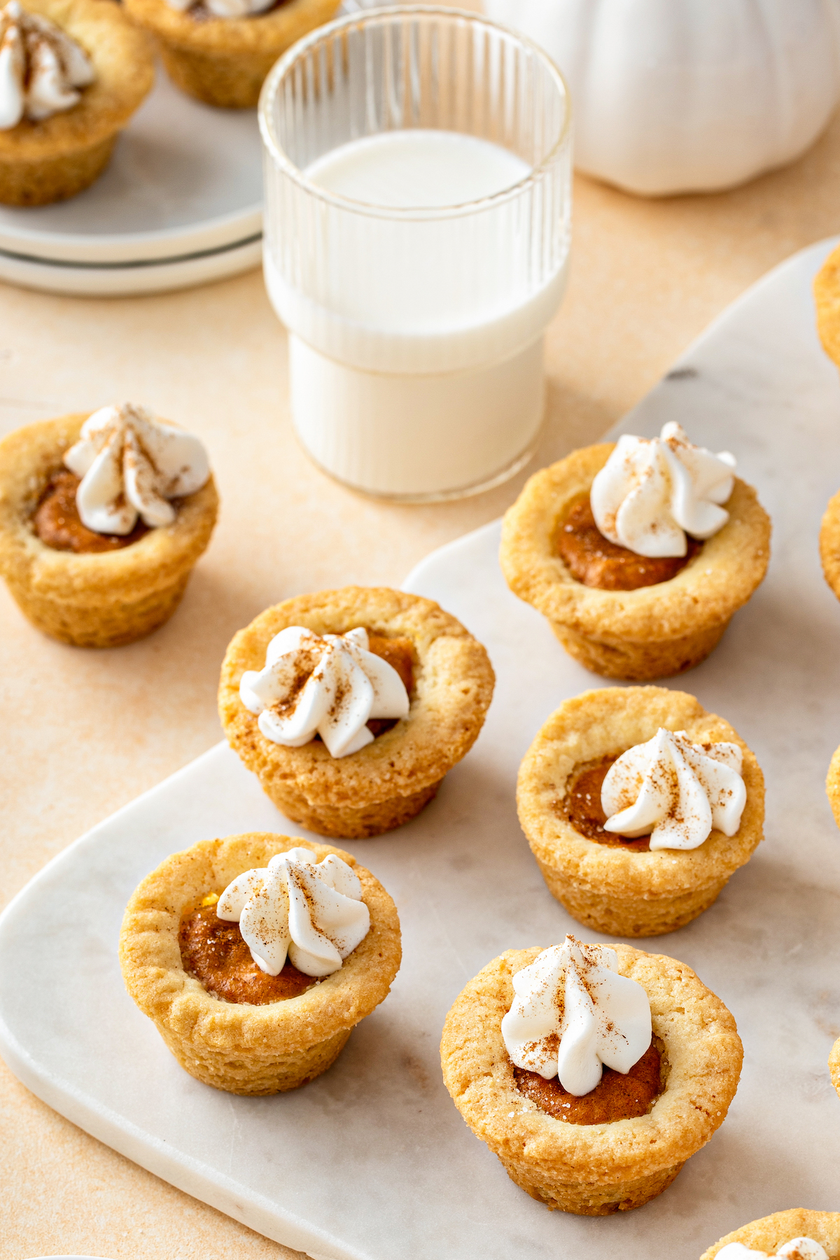 Pumpkin pie cookies on a white cutting board, with a glass of milk.