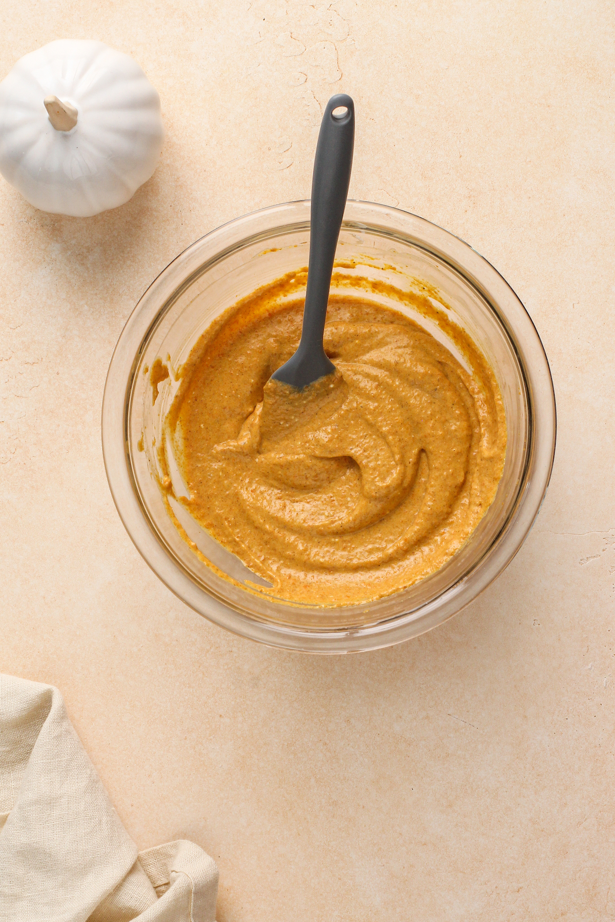 Creamy pumpkin pie filling in a bowl with a spatula.