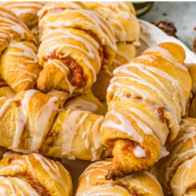 A stack of pumpkin crescent rolls on a white serving plate.