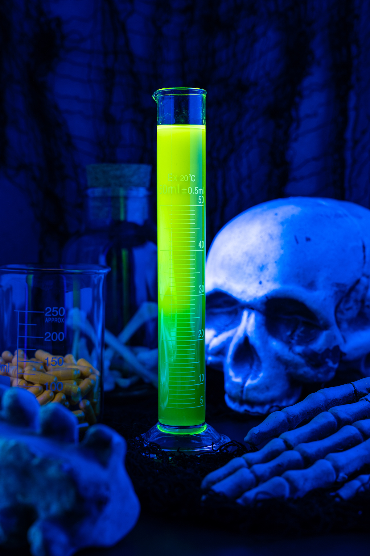 A glowing halloween shot in a test tube with a skeleton in the back ground.
