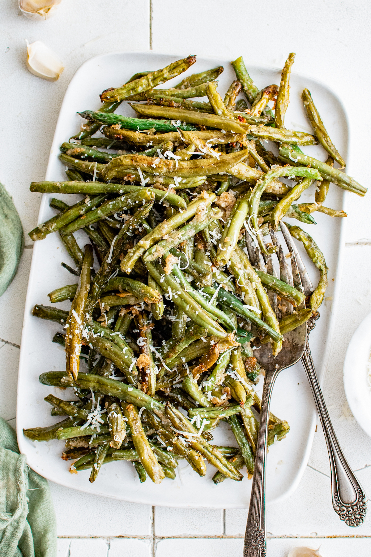 A rectangular white serving platter piled with roasted green beans.