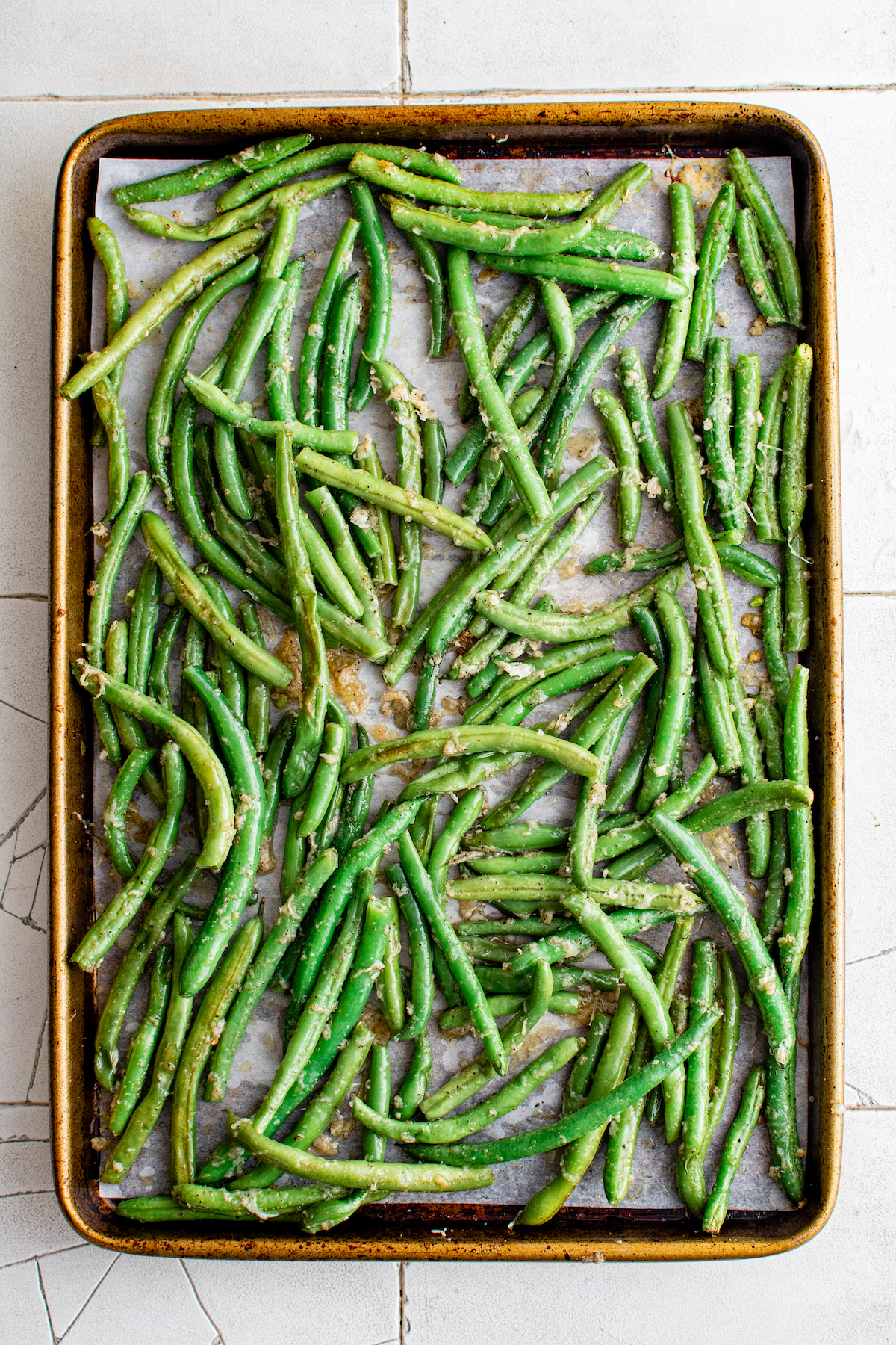 A sheet pan with oiled, seasoned green beans on it.