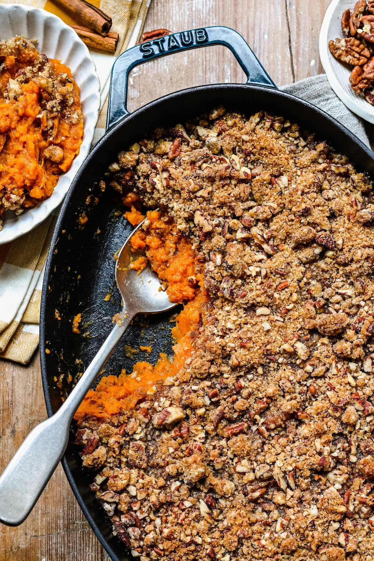 An overhead shot of a sweet potato casserole in a cast-iron baking dish, topped with chopped pecan topping.
