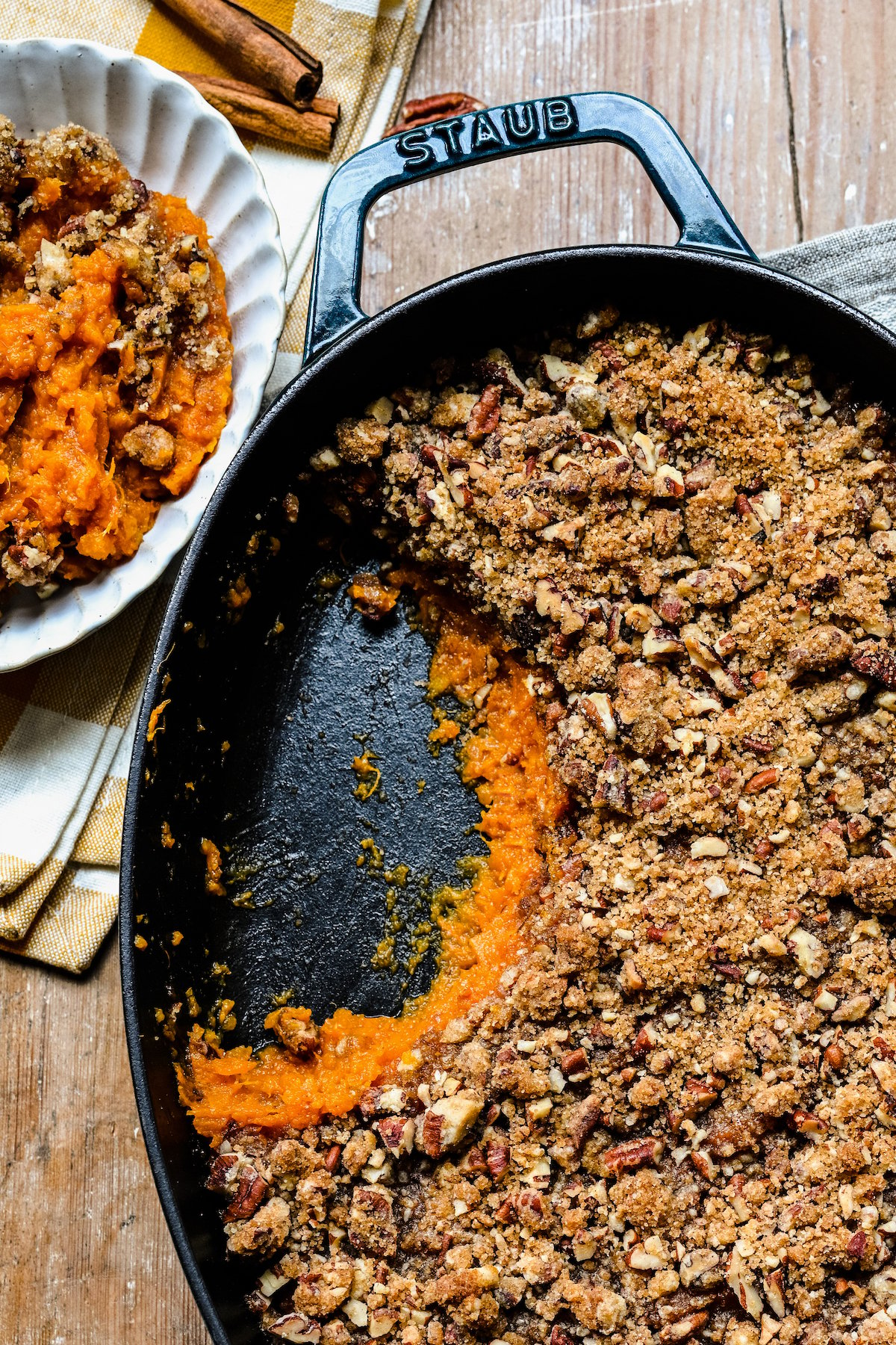 A sweet potato casserole with a serving scooped out and placed on a small plate.