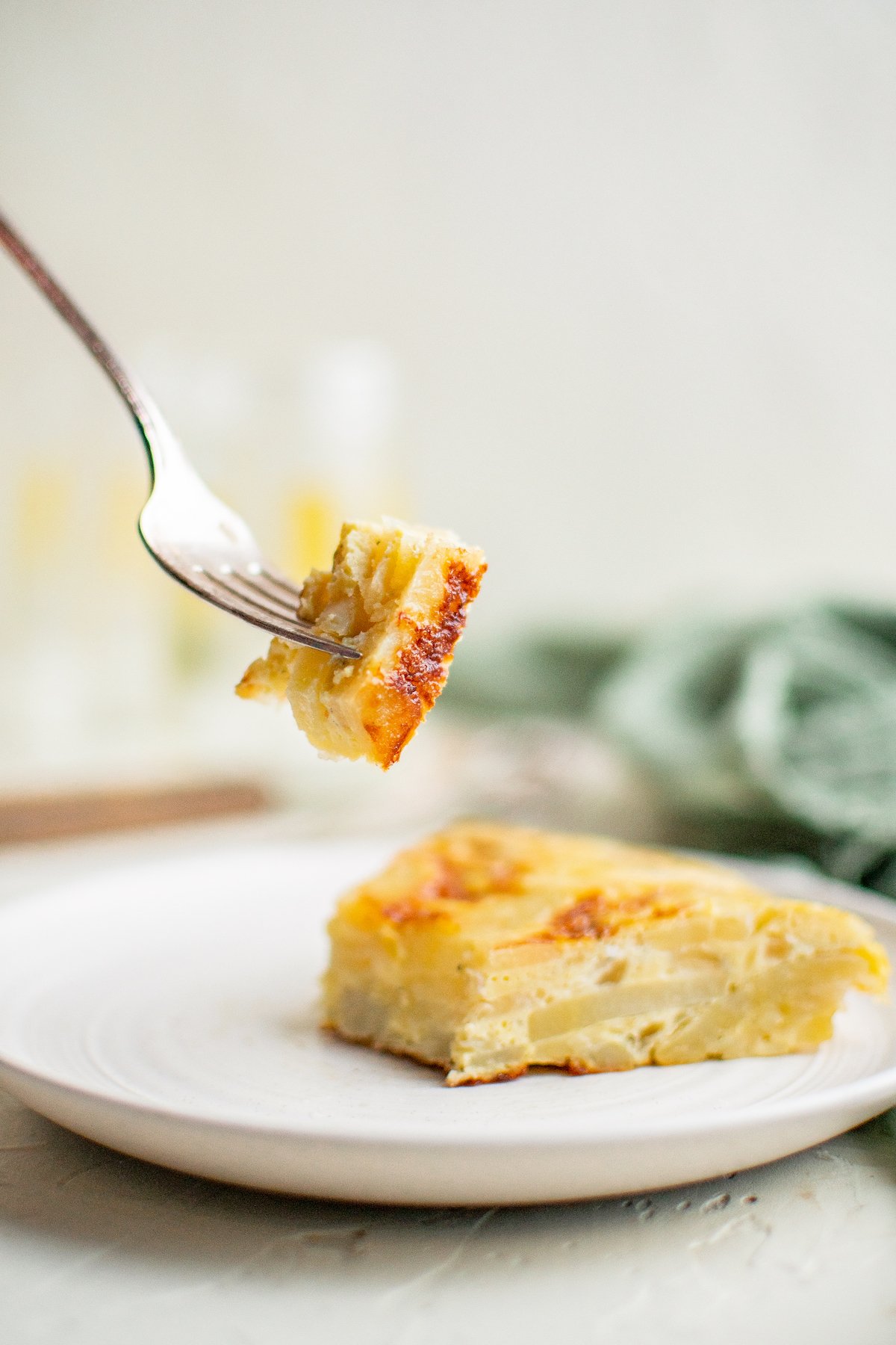A plate with a slice of tortilla española, with a fork taking a bite away