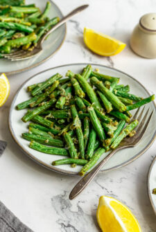 A plate of cooked green beans, wilted and lightly caramelized.