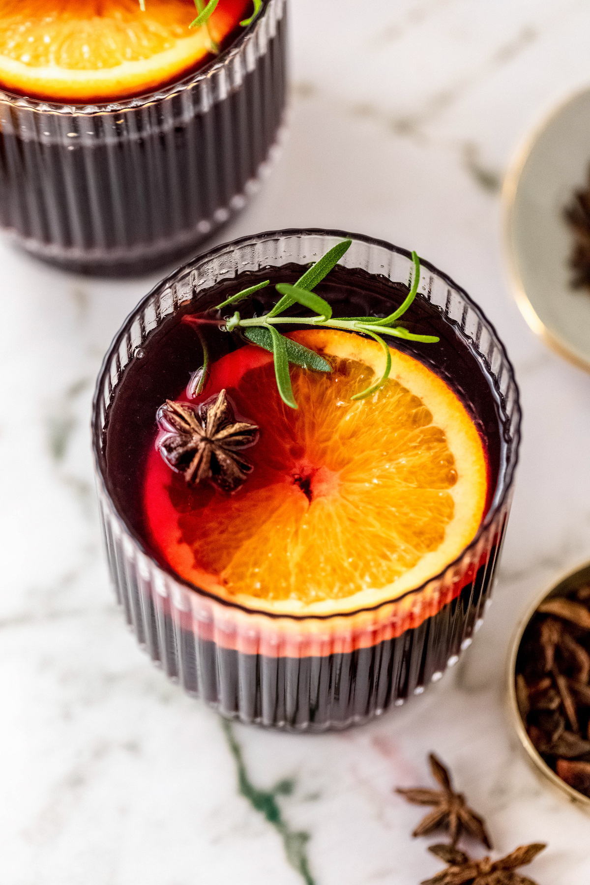 Mulled wine garnished with an orange slice, star anise, and rosemary.